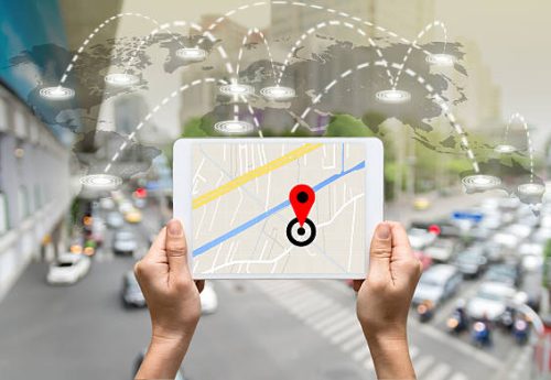 female hands holding a tablet showing part of navigator map on connection line over the world map with blurred photo of traffic jam, Navigation concept,Elements of this image furnished by NASA